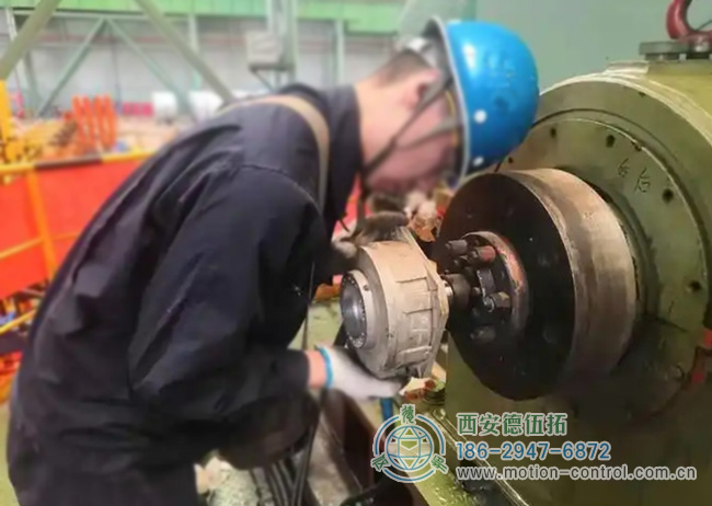 图为工人为彩涂酸轧轧机回装编码器的照片